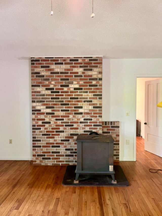 details with a textured ceiling, hardwood / wood-style floors, and a wood stove