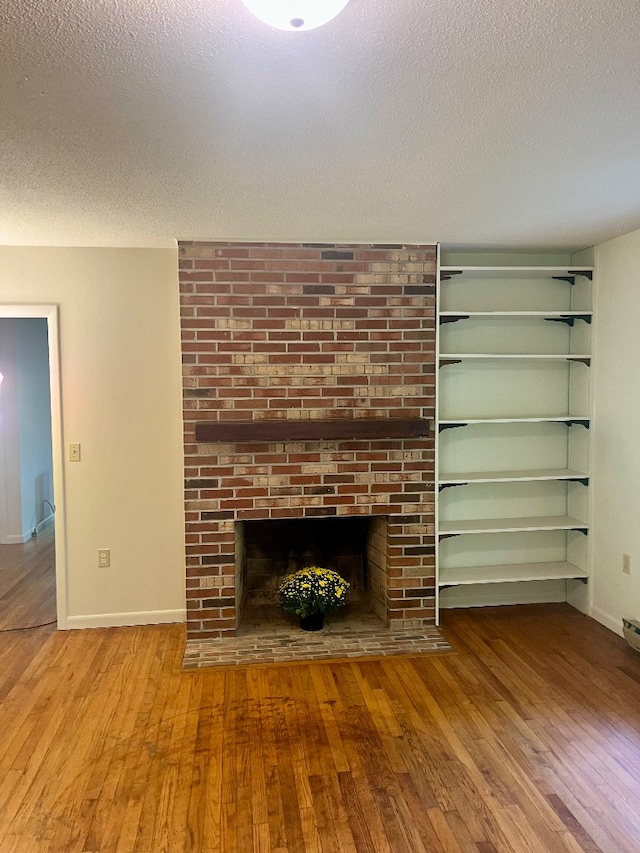 unfurnished living room with a textured ceiling, a fireplace, and light hardwood / wood-style flooring