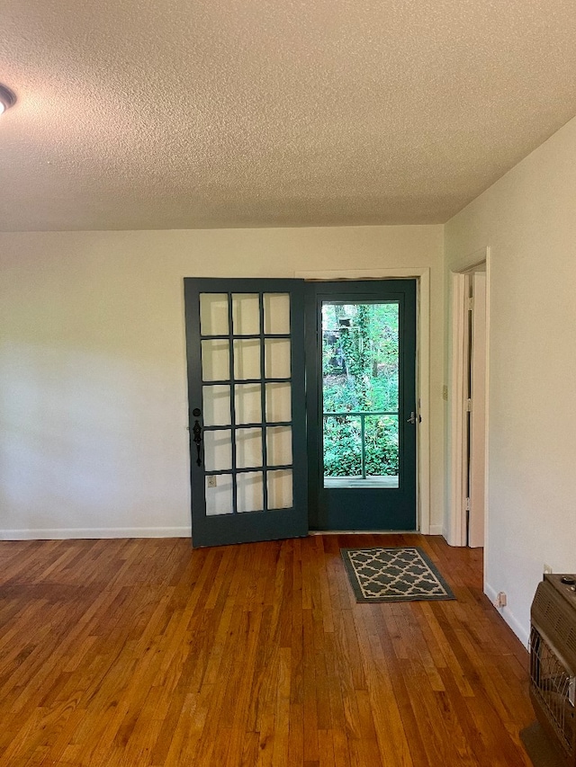 entryway featuring wood-type flooring, a textured ceiling, and heating unit