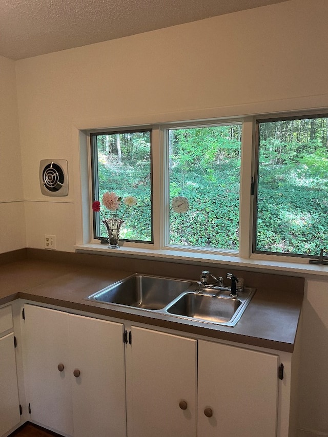 kitchen featuring a textured ceiling, sink, and white cabinets