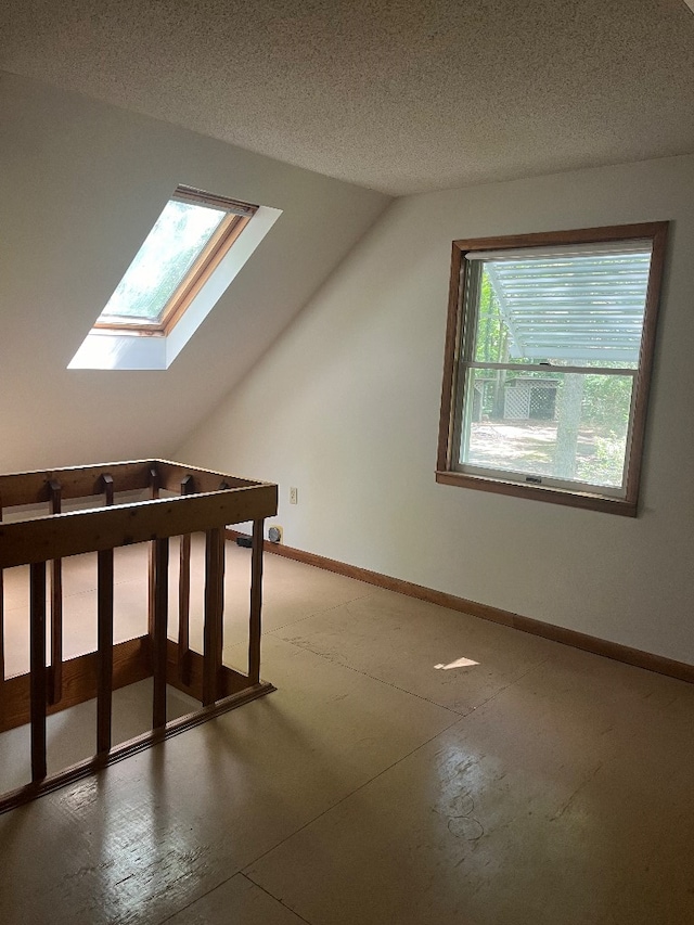 additional living space featuring a textured ceiling and vaulted ceiling with skylight