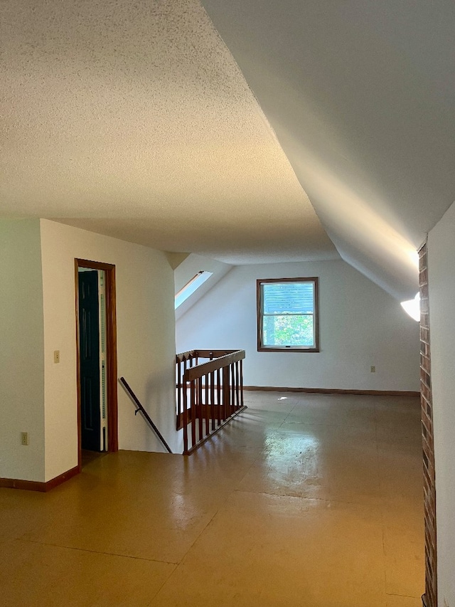 additional living space featuring a textured ceiling and lofted ceiling with skylight