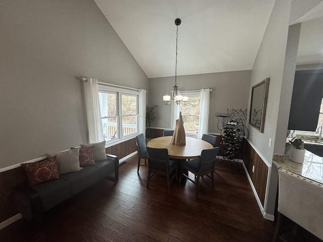 dining space featuring an inviting chandelier, dark hardwood / wood-style floors, high vaulted ceiling, and wood walls