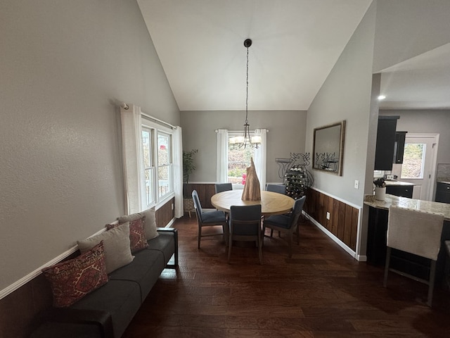 dining area featuring an inviting chandelier, dark hardwood / wood-style flooring, high vaulted ceiling, and wood walls