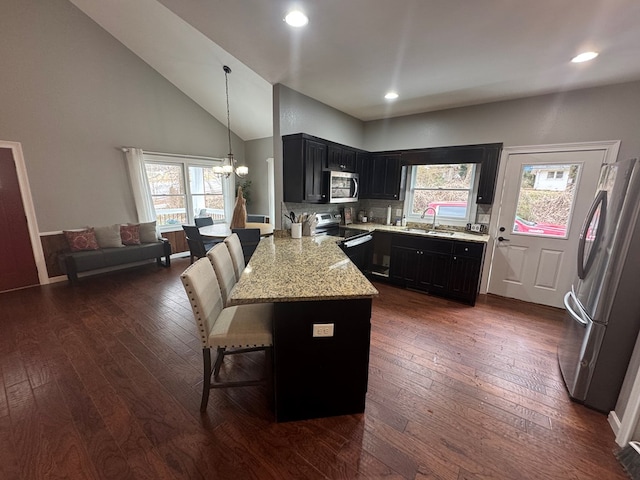 kitchen featuring a breakfast bar, sink, an inviting chandelier, pendant lighting, and stainless steel appliances