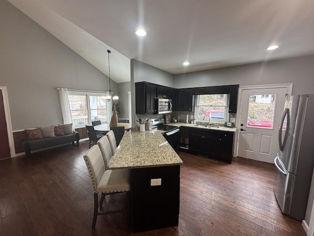 kitchen featuring a breakfast bar, decorative light fixtures, a chandelier, appliances with stainless steel finishes, and dark hardwood / wood-style floors