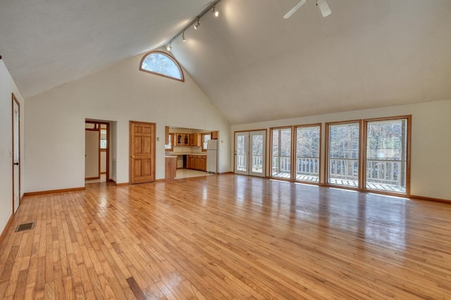 unfurnished living room featuring visible vents, plenty of natural light, high vaulted ceiling, and light wood-style flooring