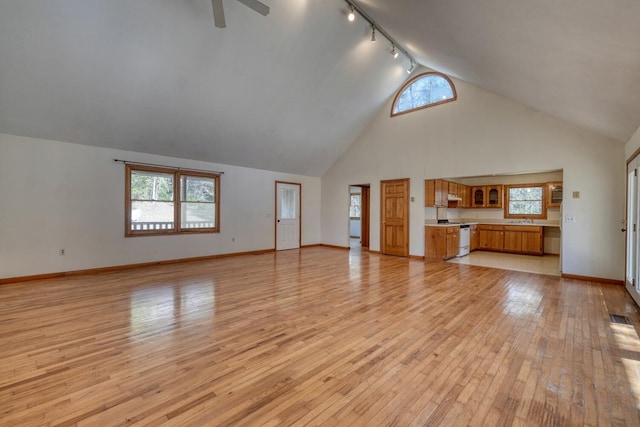 unfurnished living room featuring baseboards, light wood-type flooring, rail lighting, high vaulted ceiling, and a ceiling fan