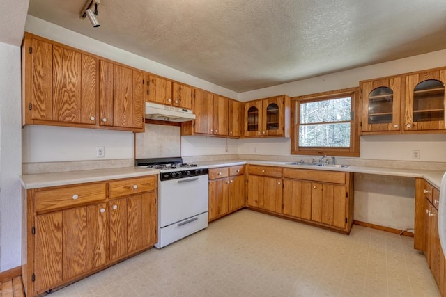 kitchen featuring white gas range, light floors, under cabinet range hood, and a sink