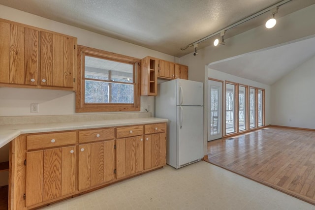 kitchen featuring vaulted ceiling, light floors, freestanding refrigerator, and light countertops