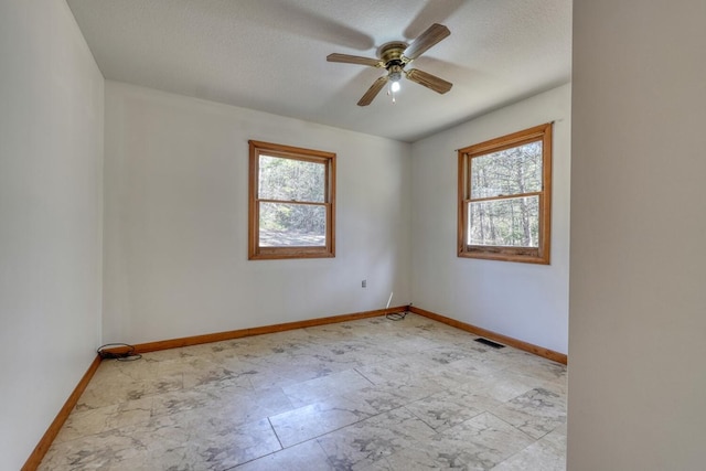 spare room with baseboards, visible vents, a wealth of natural light, and ceiling fan