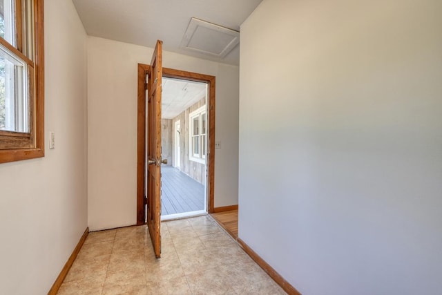 hallway featuring attic access, light tile patterned flooring, and baseboards