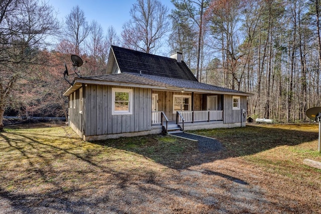 view of front of property featuring a front yard, board and batten siding, covered porch, and a chimney