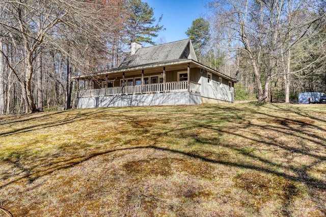 exterior space featuring board and batten siding, a porch, a front lawn, and a chimney