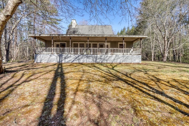 view of front of property featuring a chimney, covered porch, and a front lawn