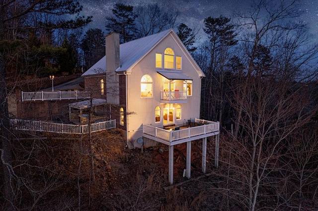 rear view of property with a balcony, a chimney, and metal roof