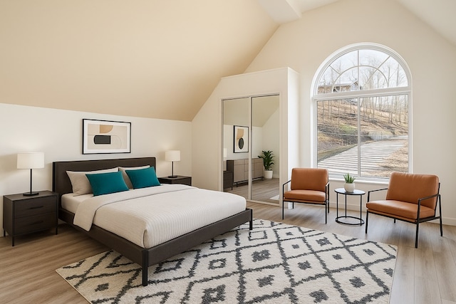 bedroom with vaulted ceiling, a closet, light wood-type flooring, and baseboards