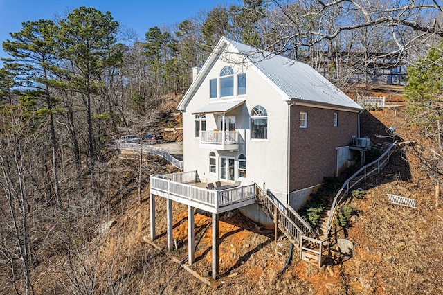 view of side of home with a balcony, stairway, metal roof, and a deck