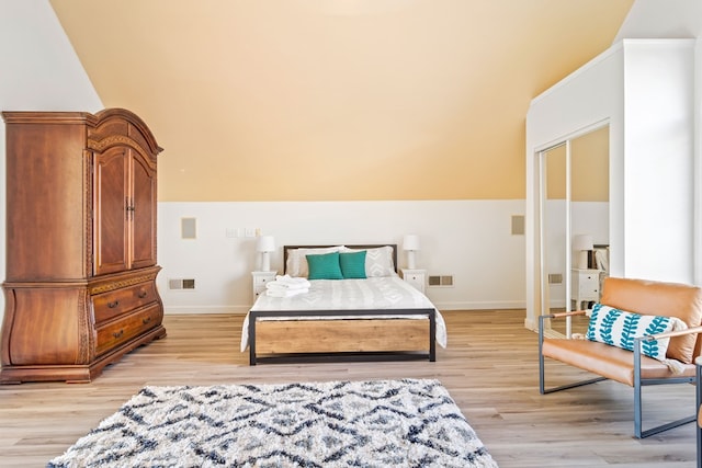 bedroom featuring light wood-style floors, baseboards, and vaulted ceiling