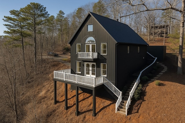 rear view of property with french doors, a balcony, and stairway