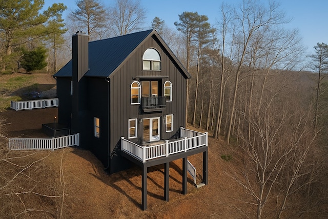 view of front facade featuring a balcony, a chimney, and board and batten siding