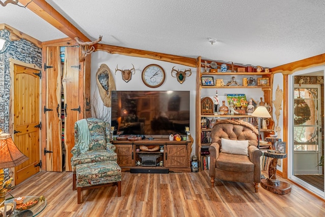 living area featuring beam ceiling, a textured ceiling, and wood finished floors