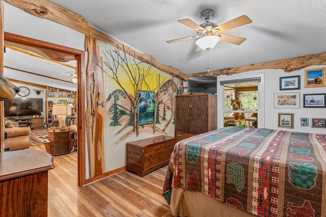 bedroom with light wood-type flooring, ceiling fan, and a textured ceiling