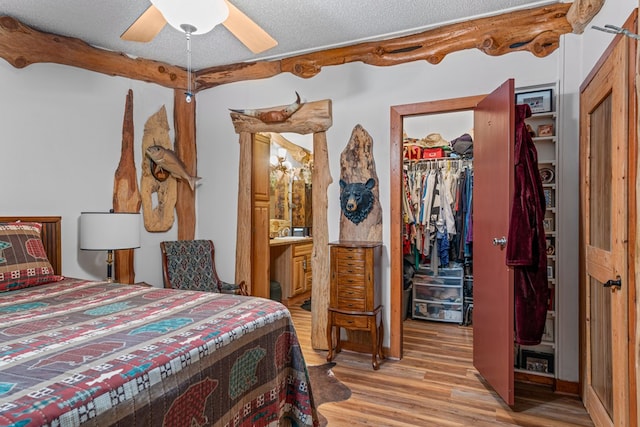 bedroom with connected bathroom, light wood-style flooring, a spacious closet, a textured ceiling, and a closet