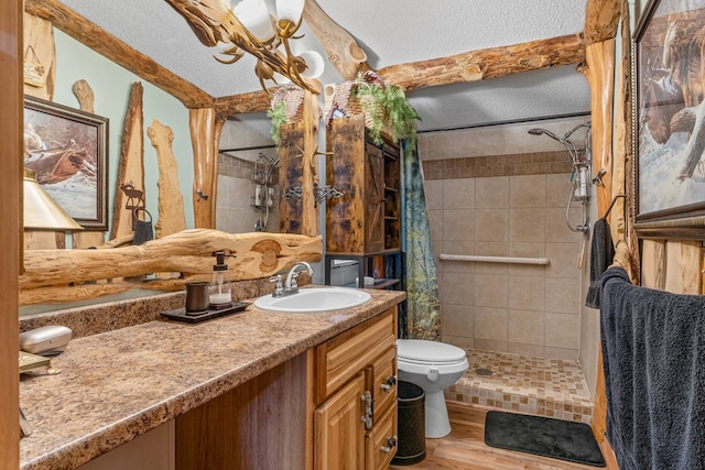 full bath with toilet, a textured ceiling, wood finished floors, and tiled shower