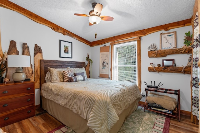 bedroom with ceiling fan, a textured ceiling, and wood finished floors