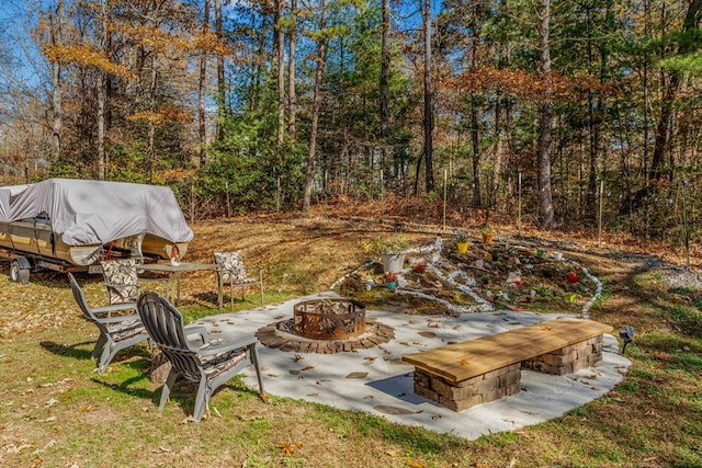 view of yard with an outdoor fire pit, a patio area, and a wooded view