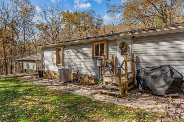 rear view of property featuring a lawn and cooling unit