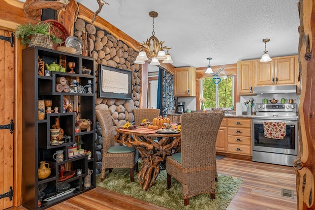 dining space featuring a textured ceiling, light wood finished floors, visible vents, and a notable chandelier