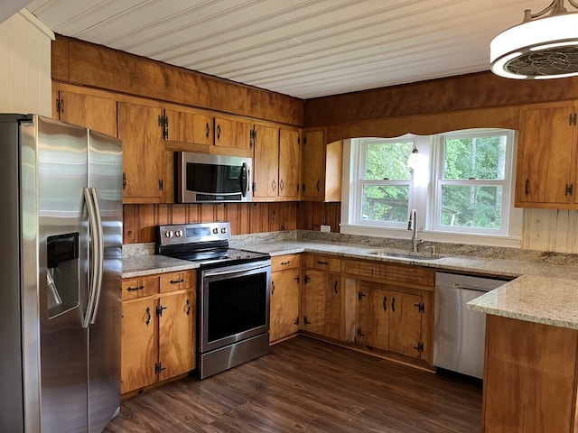 kitchen with wooden walls, stainless steel appliances, dark hardwood / wood-style floors, and sink