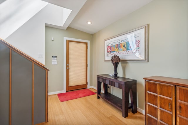 entryway featuring lofted ceiling with skylight and light hardwood / wood-style floors