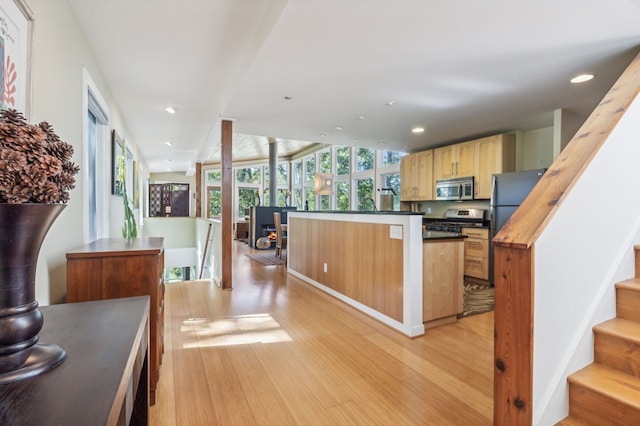 kitchen with appliances with stainless steel finishes, light hardwood / wood-style flooring, and light brown cabinetry