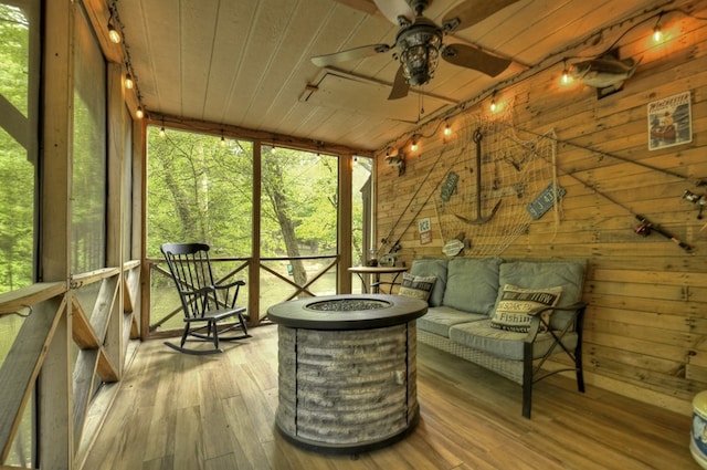 sunroom featuring plenty of natural light, ceiling fan, and an outdoor fire pit