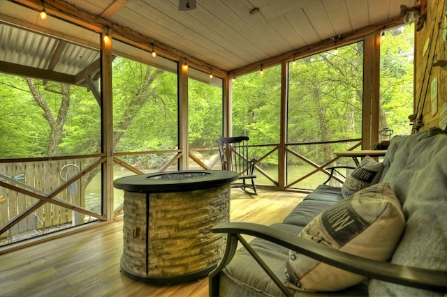 sunroom featuring an outdoor fire pit, a wealth of natural light, and a forest view