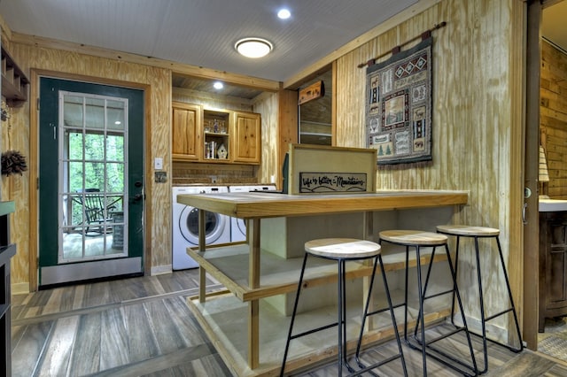 bar featuring washer / dryer, wood walls, and wood finished floors