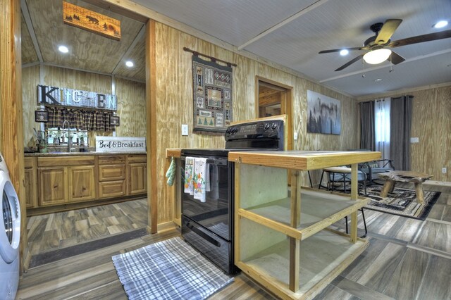 kitchen featuring wooden walls, a sink, a ceiling fan, wood finished floors, and black range with electric stovetop