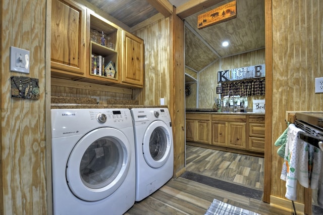 laundry room featuring washing machine and clothes dryer, wood walls, dark wood-style floors, and cabinet space