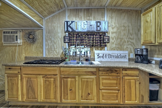 kitchen featuring a sink, a wall unit AC, wood walls, and black gas cooktop