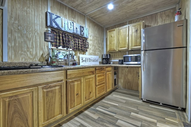 kitchen with light wood-style floors, brown cabinets, dark countertops, and stainless steel appliances