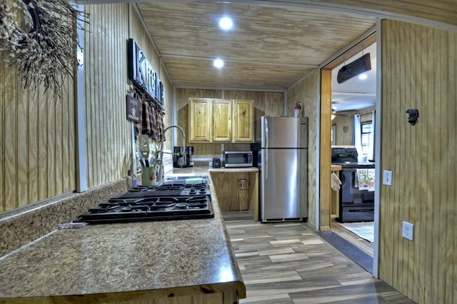 kitchen featuring wooden walls, stainless steel appliances, light countertops, and light wood-style floors