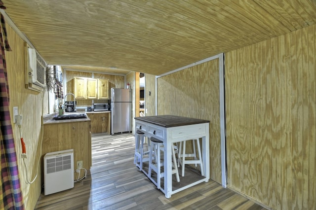 interior space with wooden walls, light wood-style floors, light countertops, stainless steel appliances, and wood ceiling
