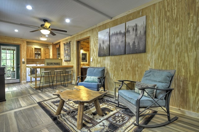 living area featuring wooden walls, recessed lighting, ceiling fan, and wood finished floors
