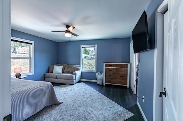 bedroom featuring ceiling fan, dark wood-style flooring, multiple windows, and baseboards