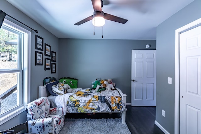 bedroom featuring dark wood-style floors, a ceiling fan, and baseboards