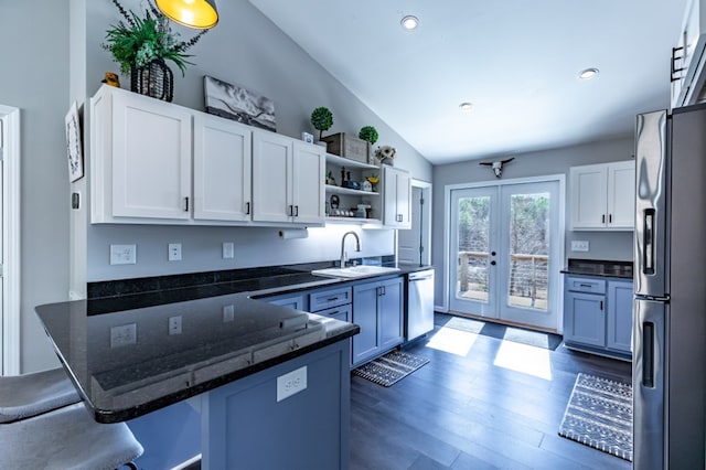 kitchen with open shelves, stainless steel dishwasher, freestanding refrigerator, a sink, and a peninsula