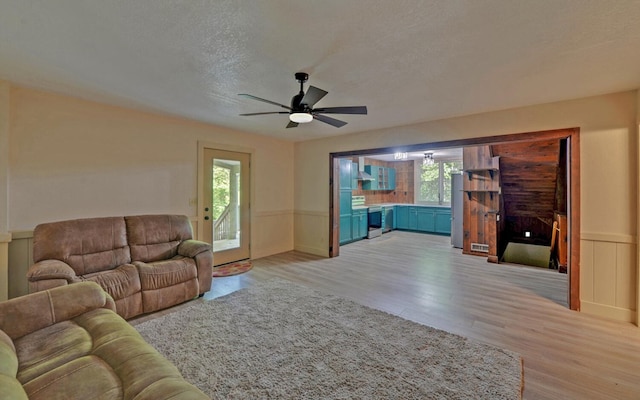 469 Hidden Valley Dr, Morganton, GA 30560 - living room featuring light wood-type flooring, ceiling fan, wainscoting, and a textured ceiling